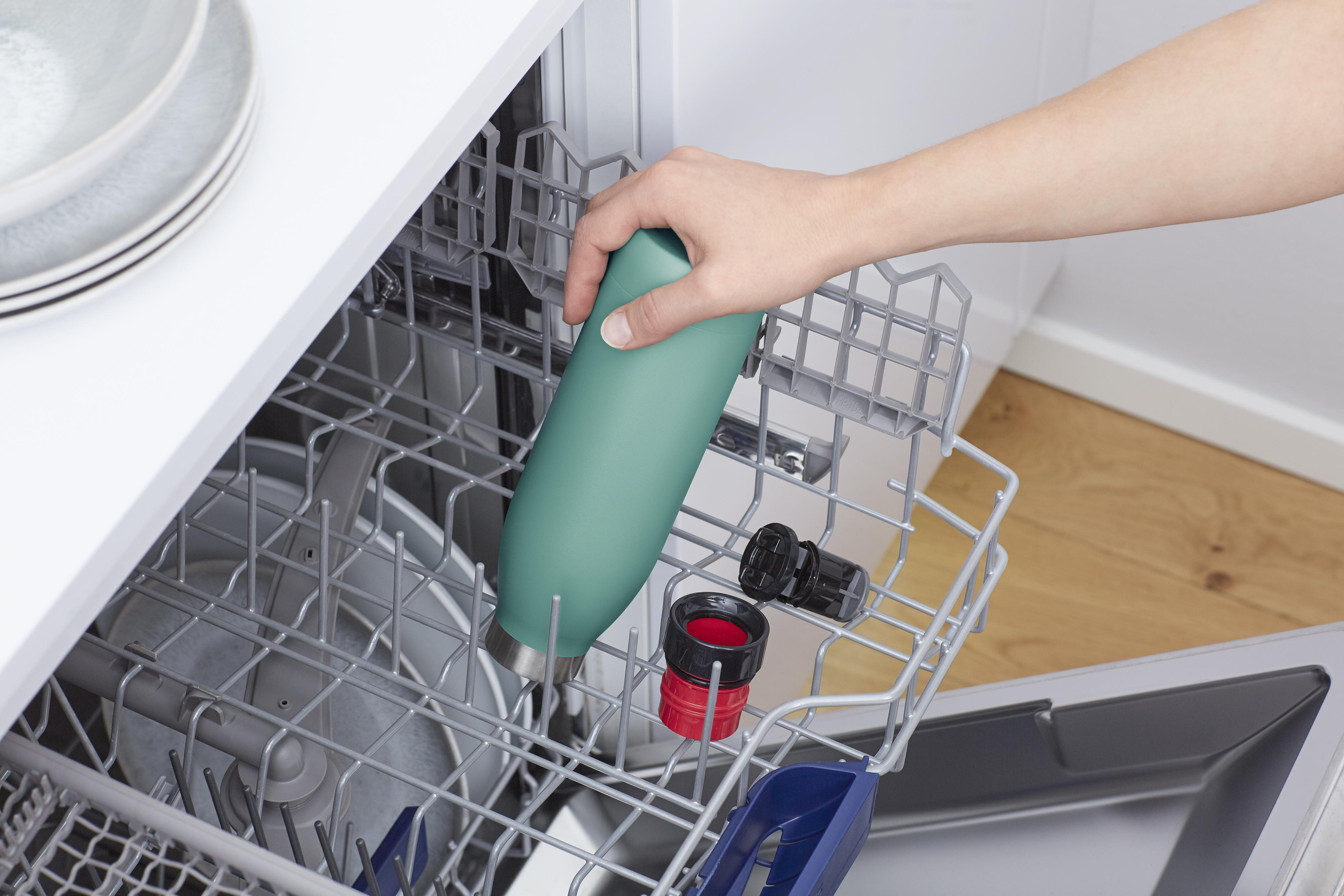 Hand platziert eine türkisfarbene Wasserflasche in einen Geschirrspüler. Andere Gegenstände sind im Gestell.
