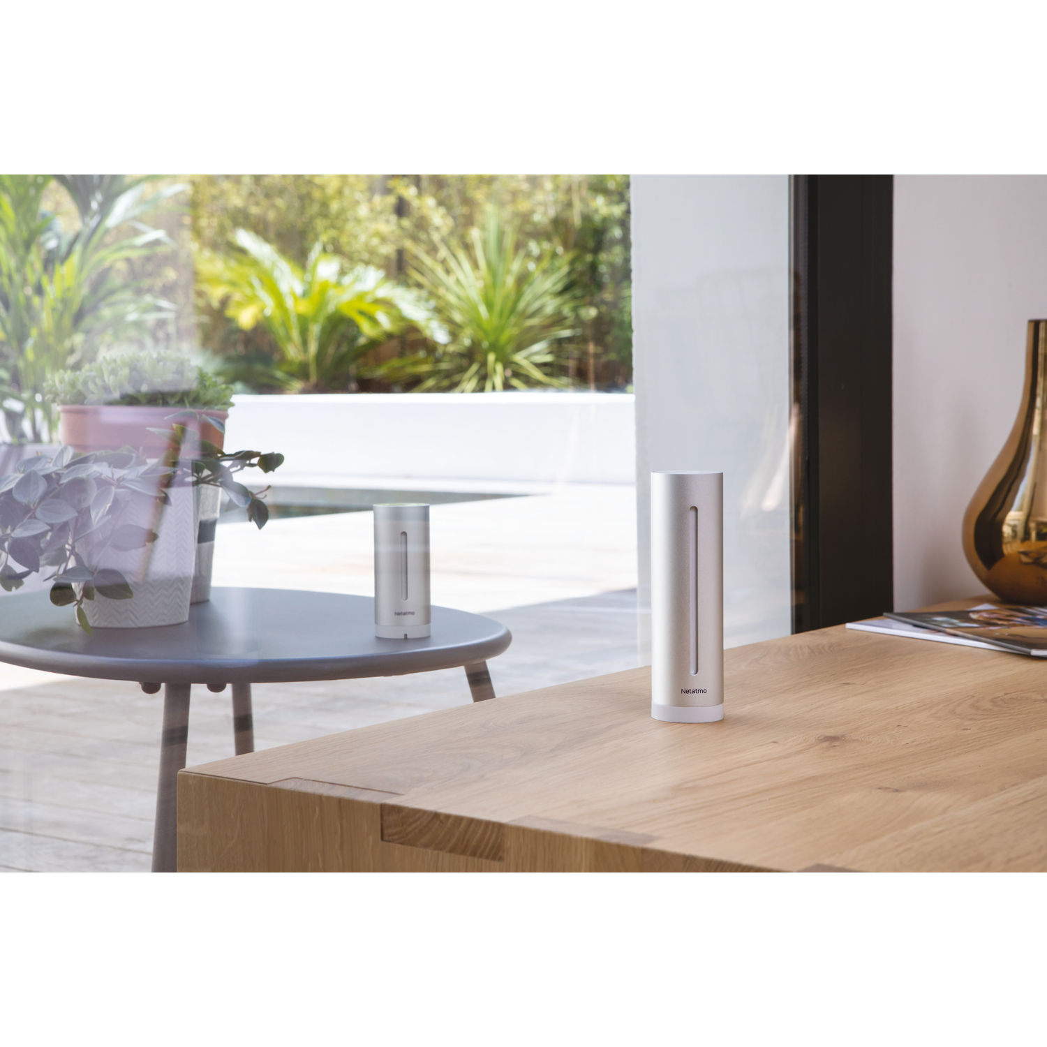 Dos dispositivos inteligentes cilíndricos plateados para el hogar sobre una superficie de madera.