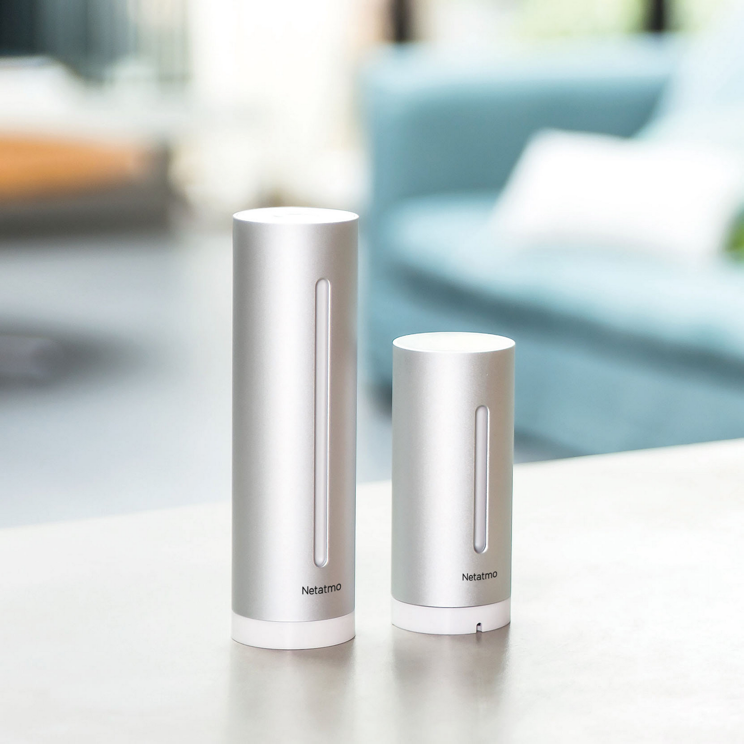Dos dispositivos inteligentes para el hogar cilíndricos plateados con el logo Netatmo.