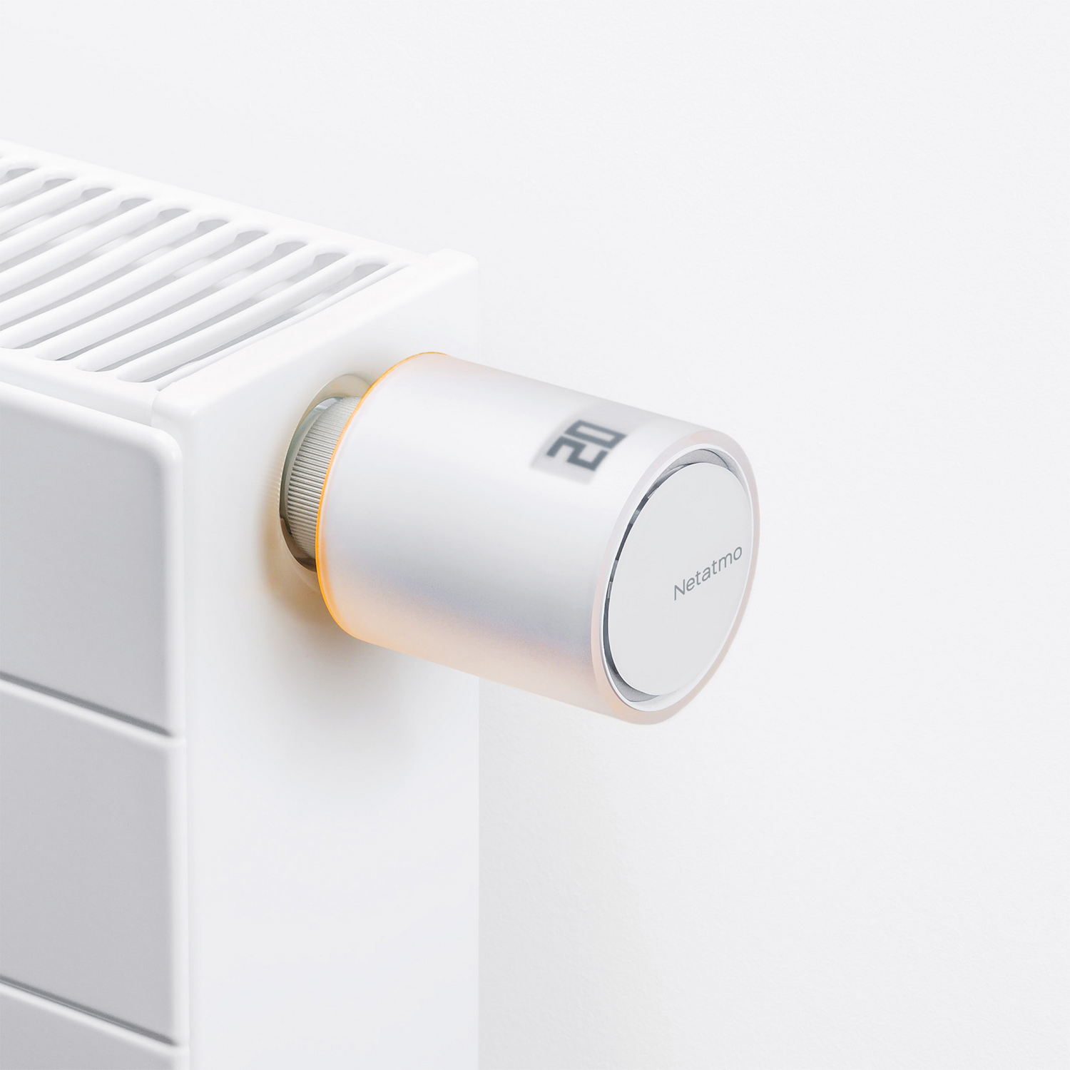 Un termostato inteligente en un radiador blanco, mostrando la temperatura.