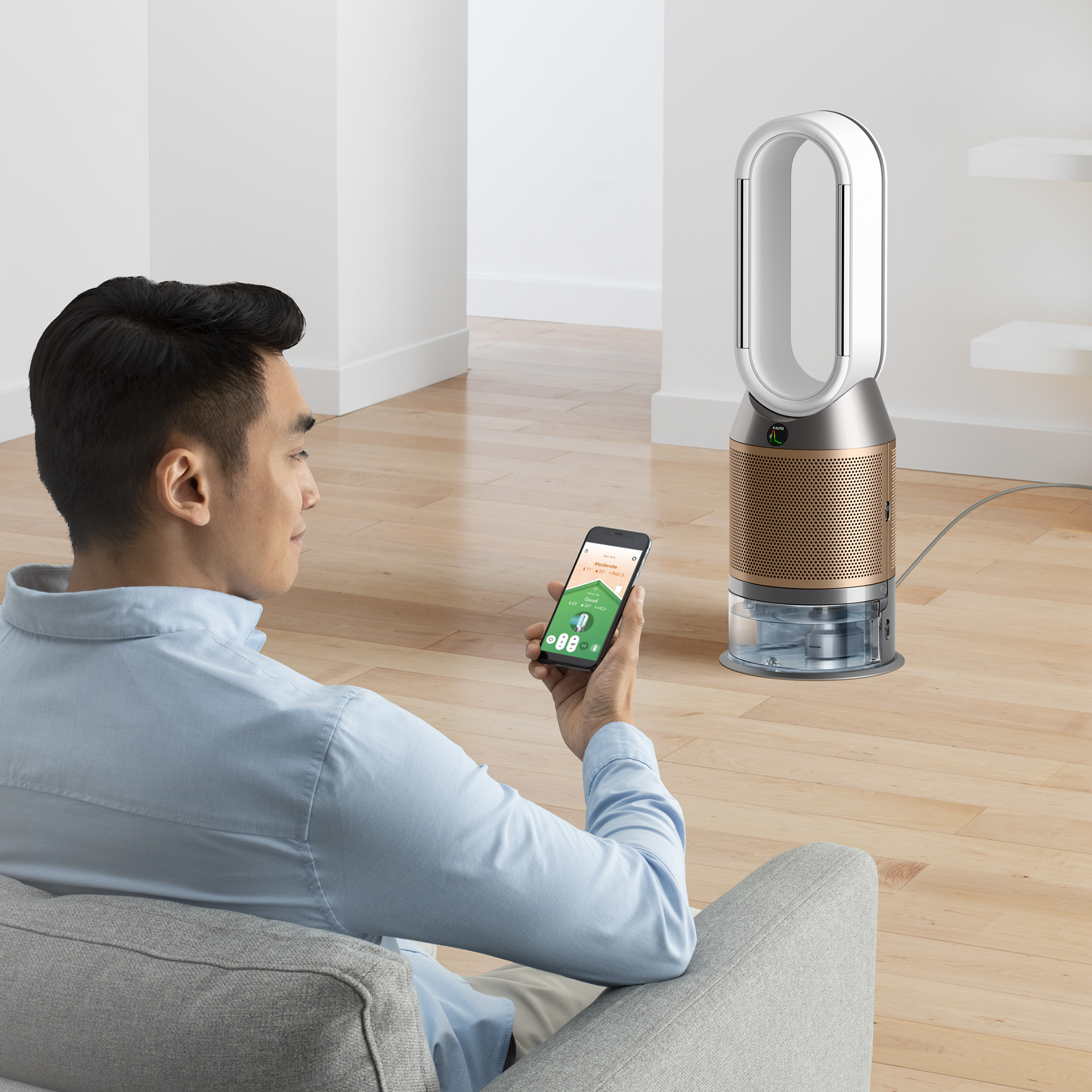 Man houdt telefoon vast, kijkt naar een slimme luchtreiniger. Modern design, houten vloer.