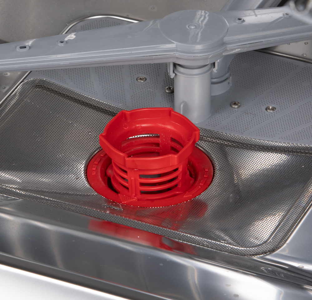 Close up of a dishwasher's inside. A red object is in the middle, with perforated metal.