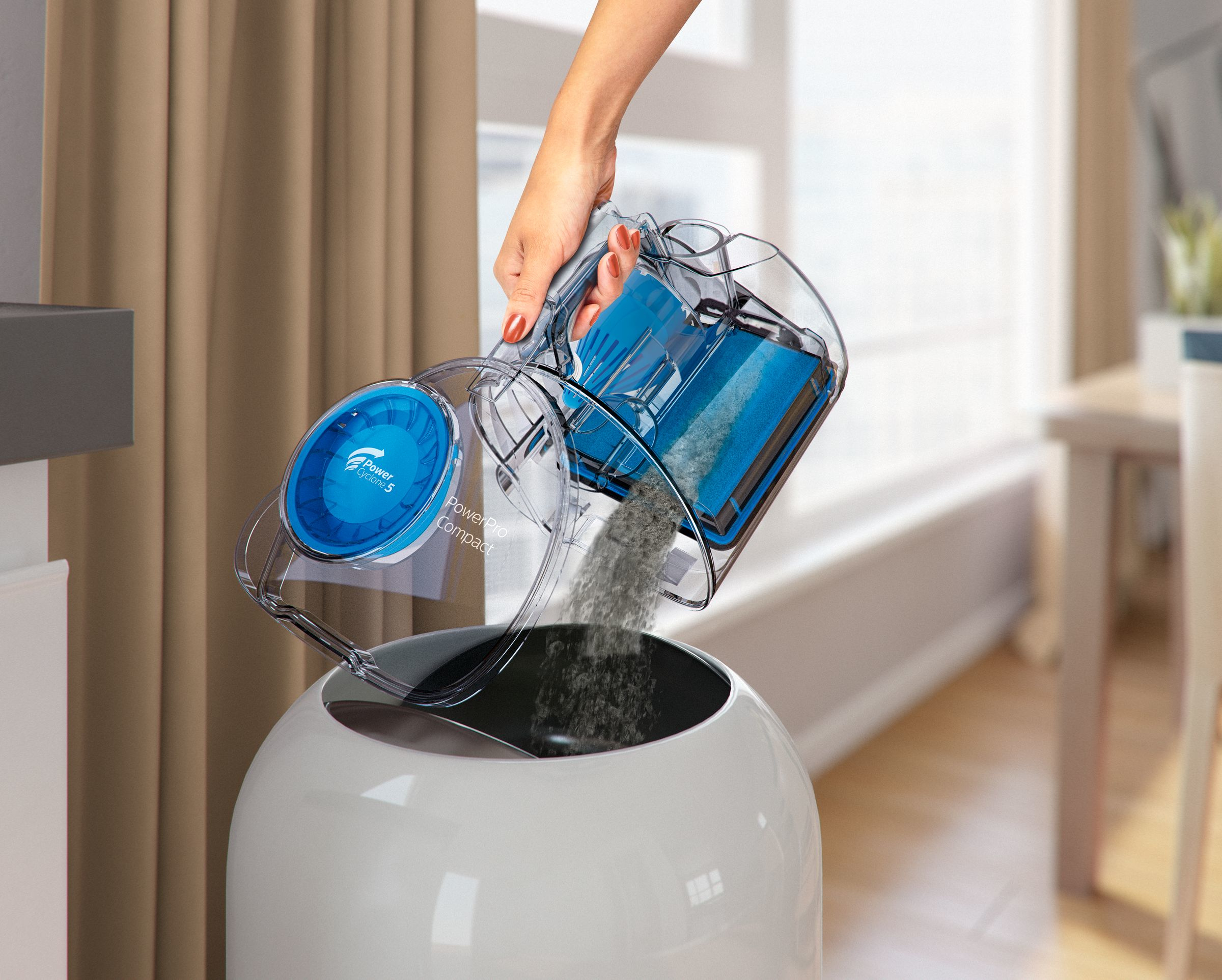 Hand emptying vacuum dust container into a white bin, with a blurred background.