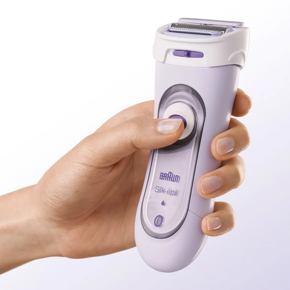 Hand holding a lavender electric epilator. White background.