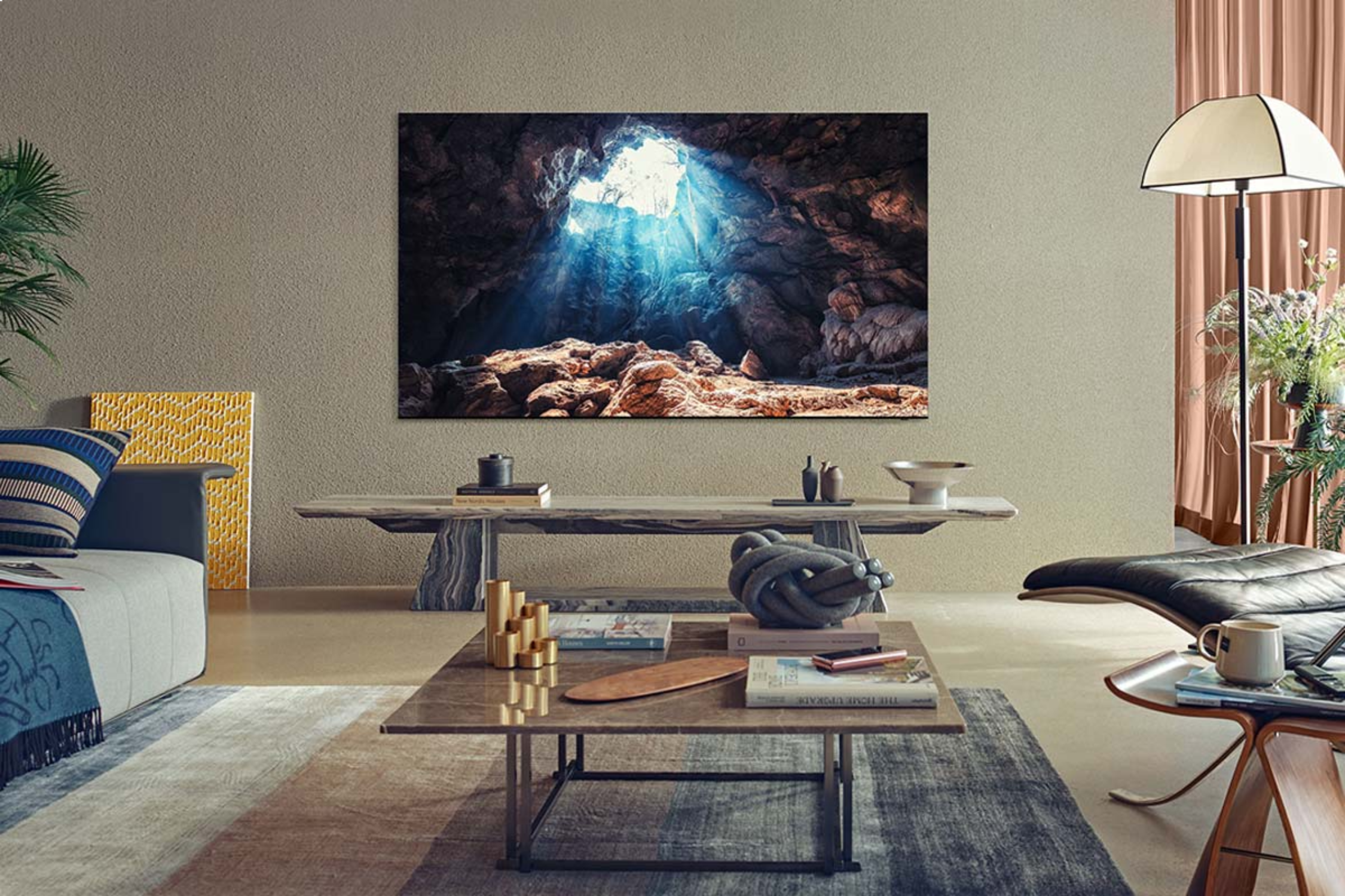 Una sala de estar con un televisor grande que muestra una escena de cueva iluminada. Muebles incluyen sofá, mesa y lámpara.