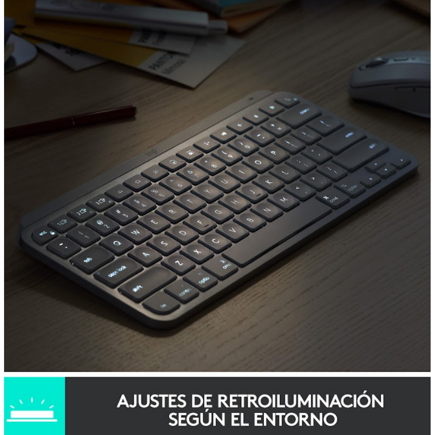 Un teclado gris oscuro con teclas iluminadas en un escritorio de madera.
