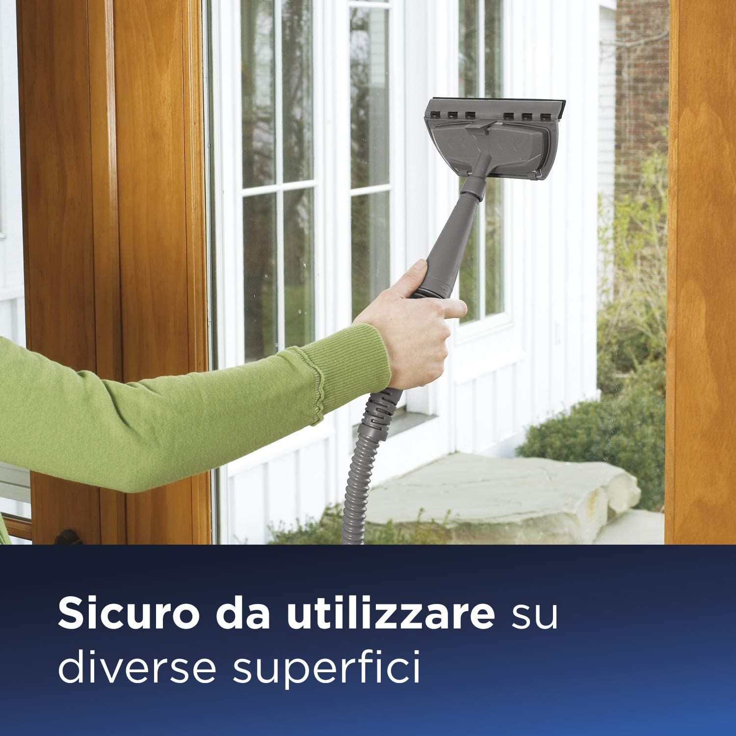 Una persona usa un pulitore a vapore su una finestra di vetro.