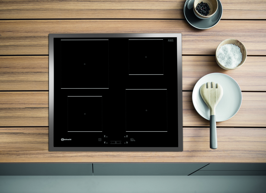 Schwarzes Induktionskochfeld mit vier Kochzonen. Holzhintergrund mit Gericht und Salz.