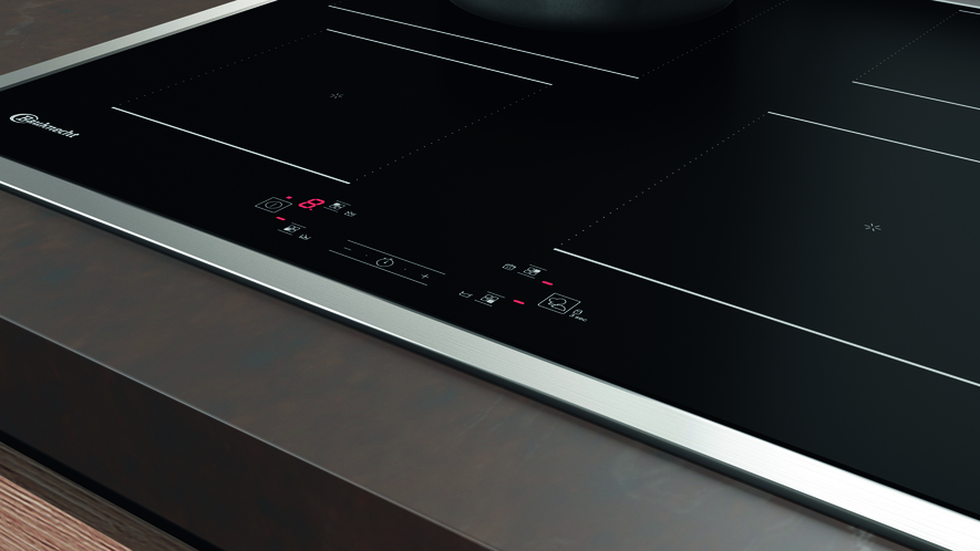 Ein schwarzes Induktionskochfeld. Es hat vier Kochzonen und Touch-Bedienelemente.