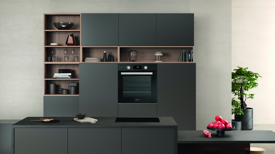 Eine moderne Küche mit dunklen Schränken, einem Ofen und einer schwarzen Arbeitsplatte mit Insel.