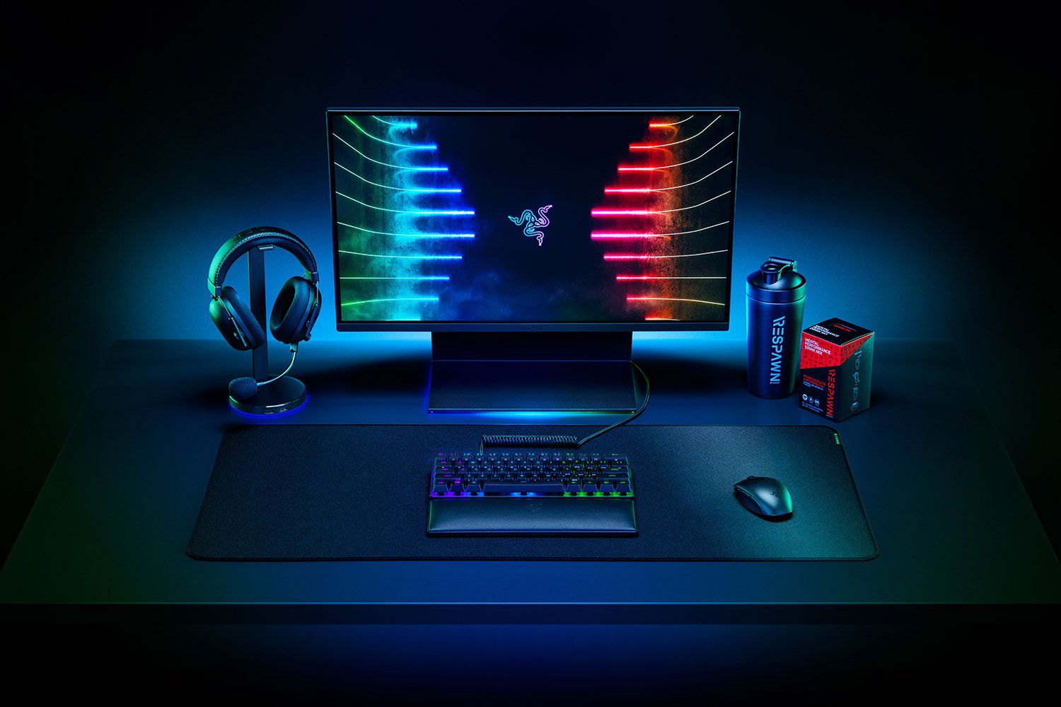 Gaming-Setup: Monitor, Kopfhörer, Tastatur, Maus, Wasserflasche und Zubehör auf schwarzer Oberfläche.