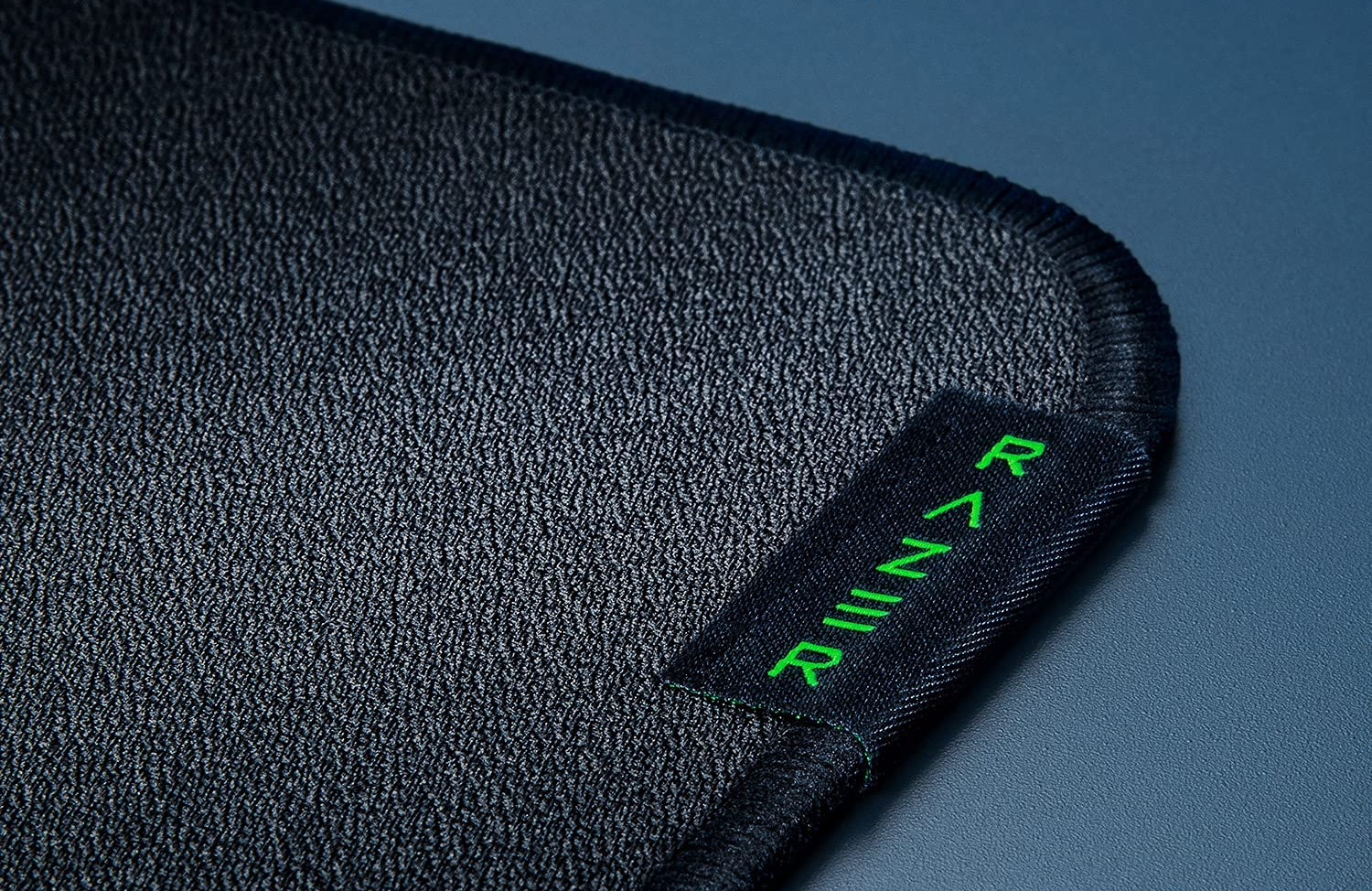 Tapis de souris Razer noir avec une étiquette Razer verte dans le coin.