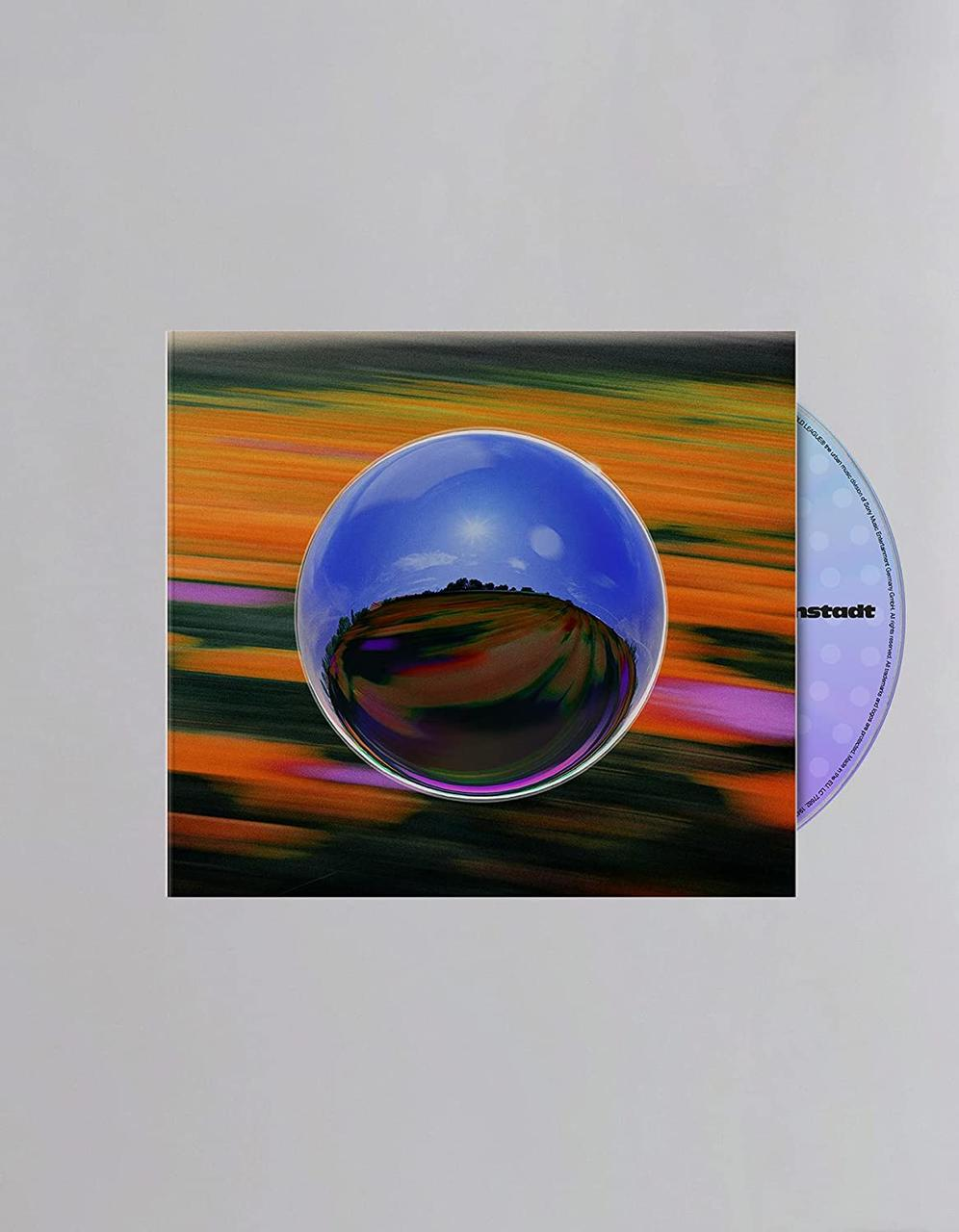 CD-Hülle mit Disc. Das Cover zeigt eine verschwommene Landschaft, die sich in einer blauen Kugel spiegelt.