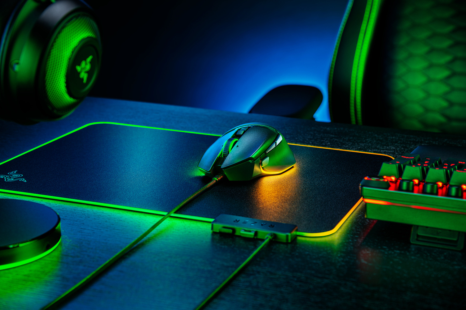 Ein Gaming-Setup mit schwarzer Maus, Mauspad, Tastatur und Kopfhörern. Grüne und blaue Lichter verstärken die Stimmung.