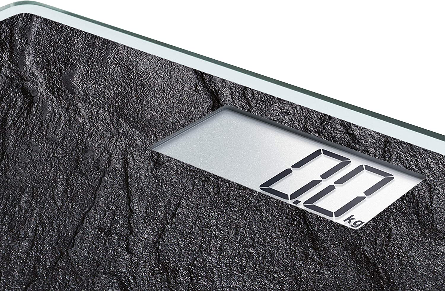 Eine Digitalwaage zeigt 0,0 kg an. Die Waage hat eine schwarze, steinartige Textur. Das Display ist silber.