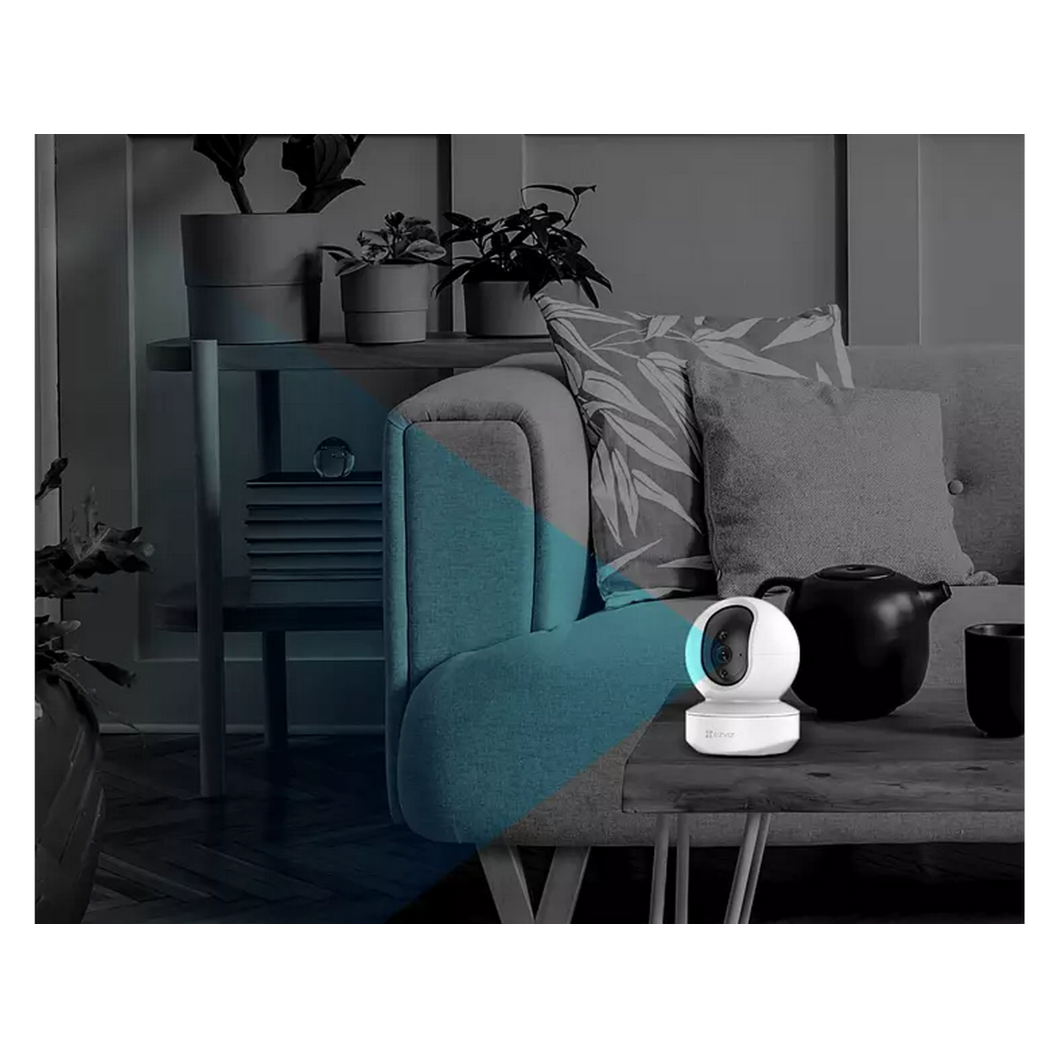 Una cámara de seguridad blanca sobre una mesa con un sofá y plantas en el fondo borroso.