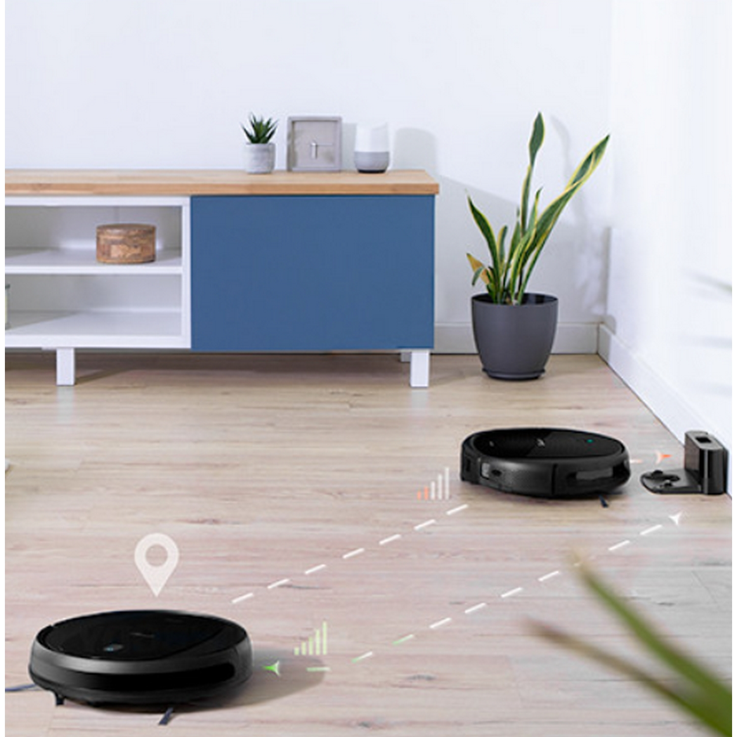 Dos robots aspiradores negros en piso de madera. Uno cerca de estación de carga. Ambiente moderno.