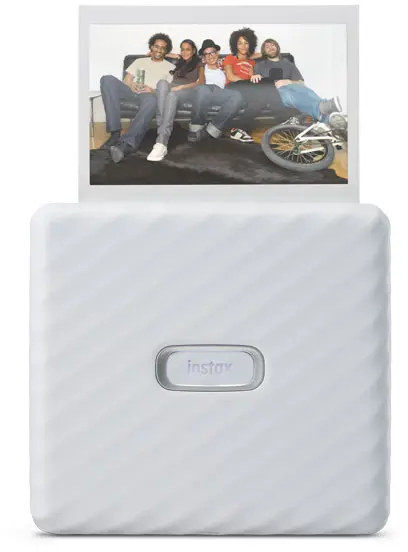 White Instax printer with a photo of friends. Printer is on a white background. Photo is being printed.