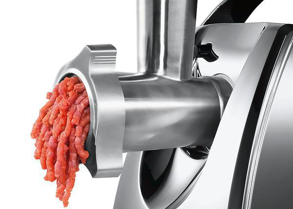 Ein Fleischwolf mit gehacktem Fleisch, das aus der vorderen Öffnung austritt.