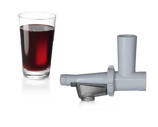Ein Glas roter Saft neben einer zerlegten Entsafterkomponente.