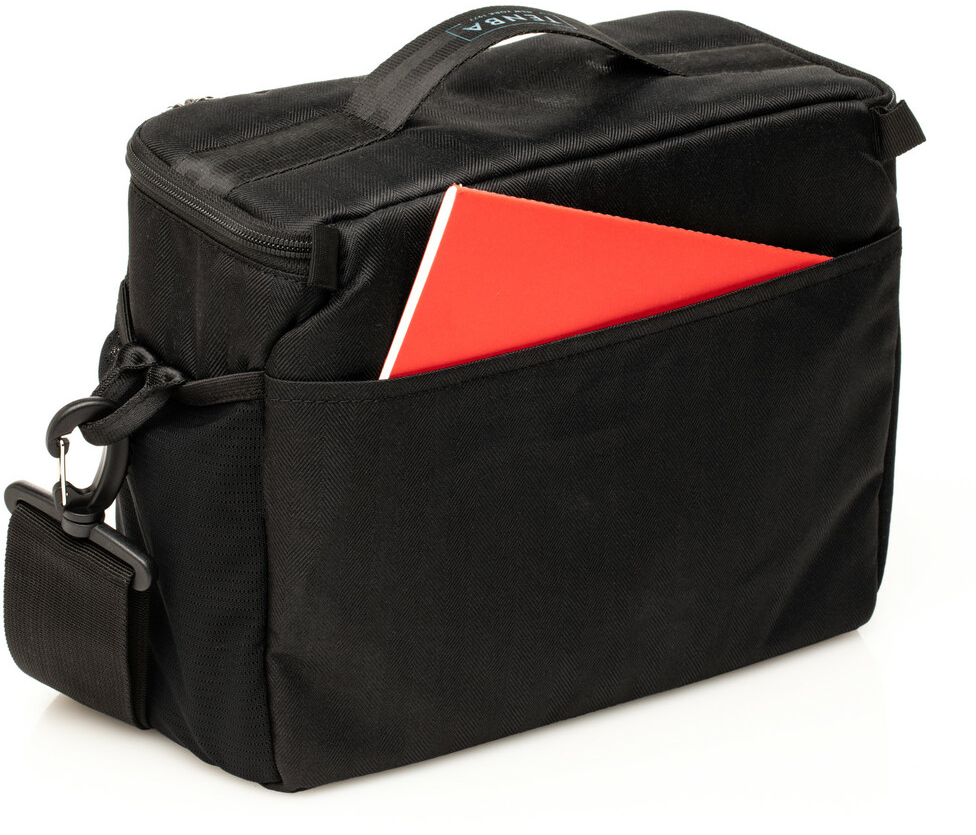Schwarze Tasche mit rotem Notizbuch in der Seitentasche. Die Tasche hat einen Schultergurt.