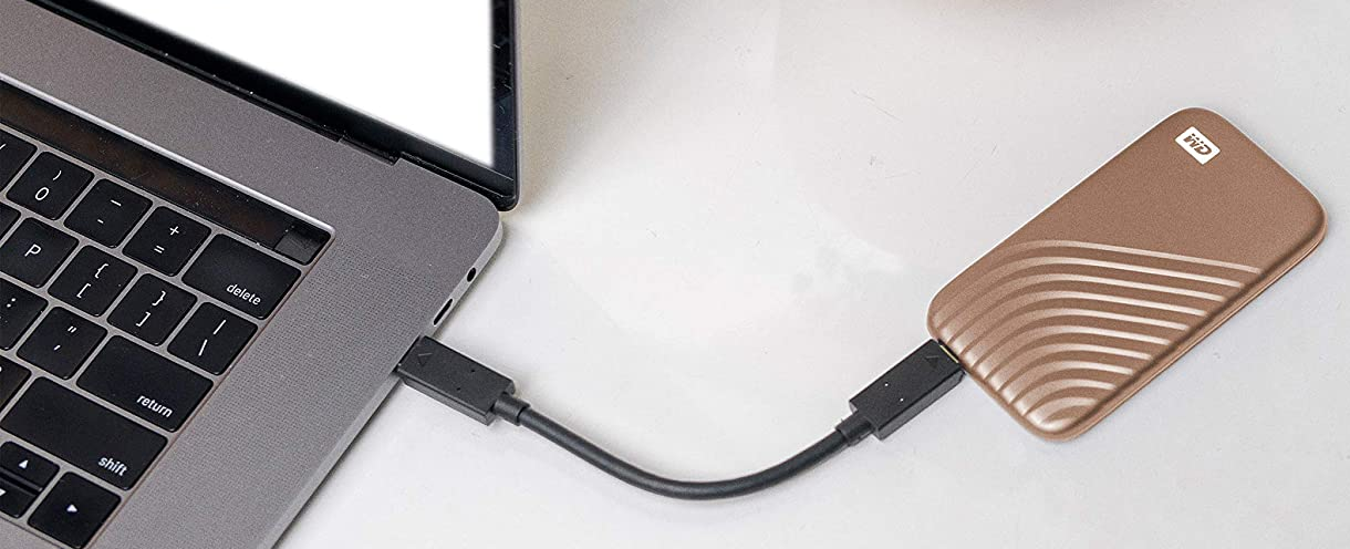 Laptop egy barna külső merevlemezhez csatlakoztatva USB kábelen keresztül.