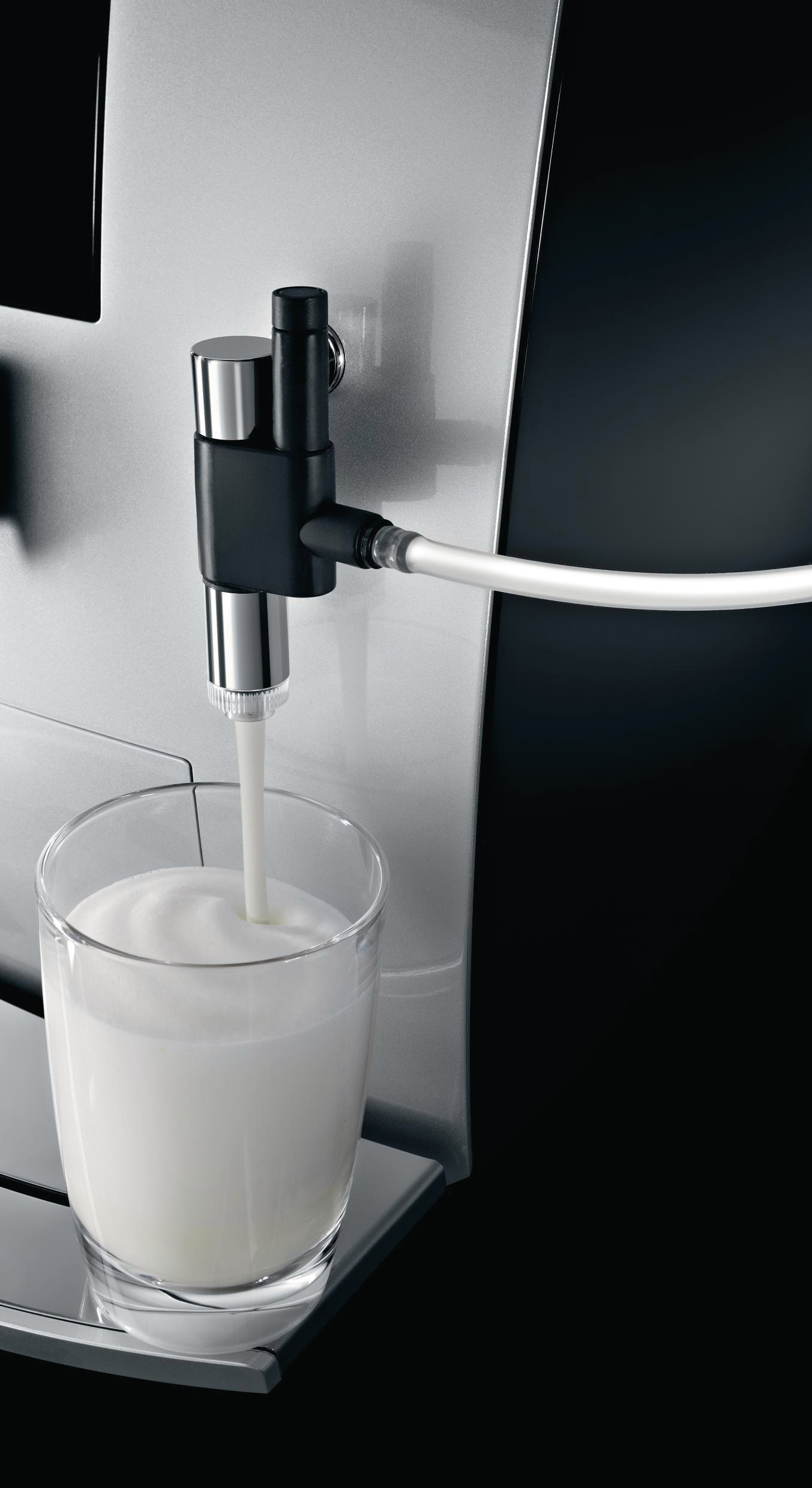Eine Kaffeemaschine, die Milch in ein Glas ausgibt. Die Maschine ist silber und schwarz.