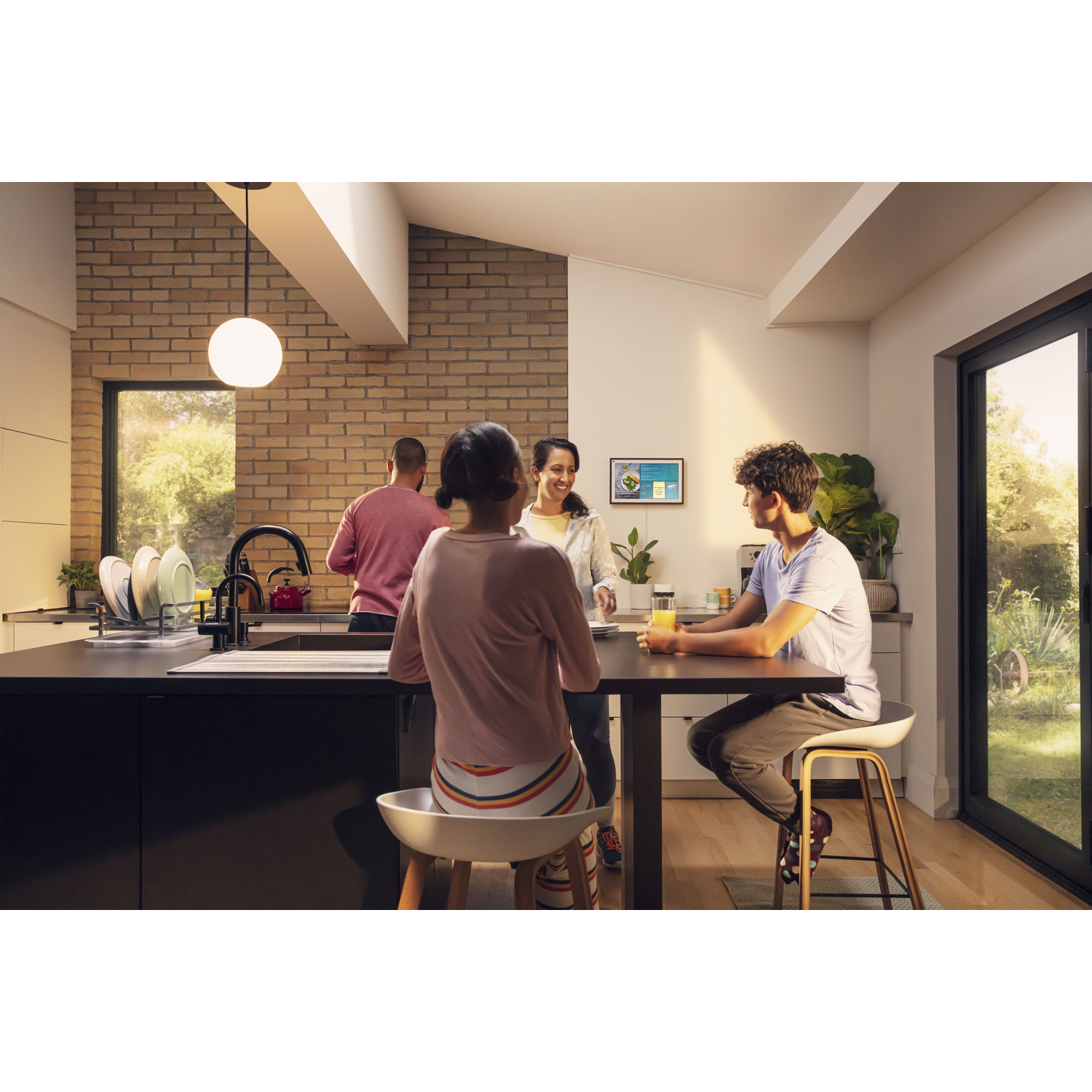 Gente en una cocina, una en una mesa usando una tableta.