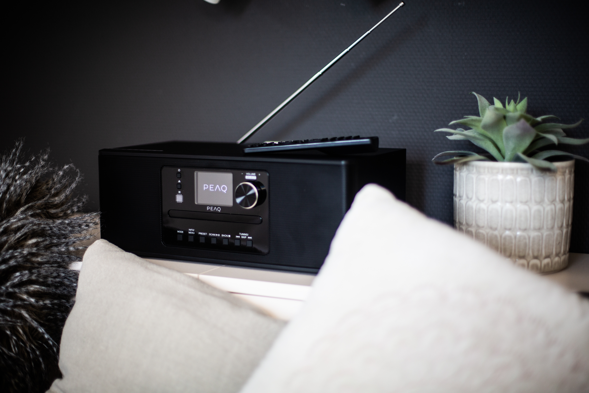 Un radio-réveil PEAQ noir avec antenne et télécommande.