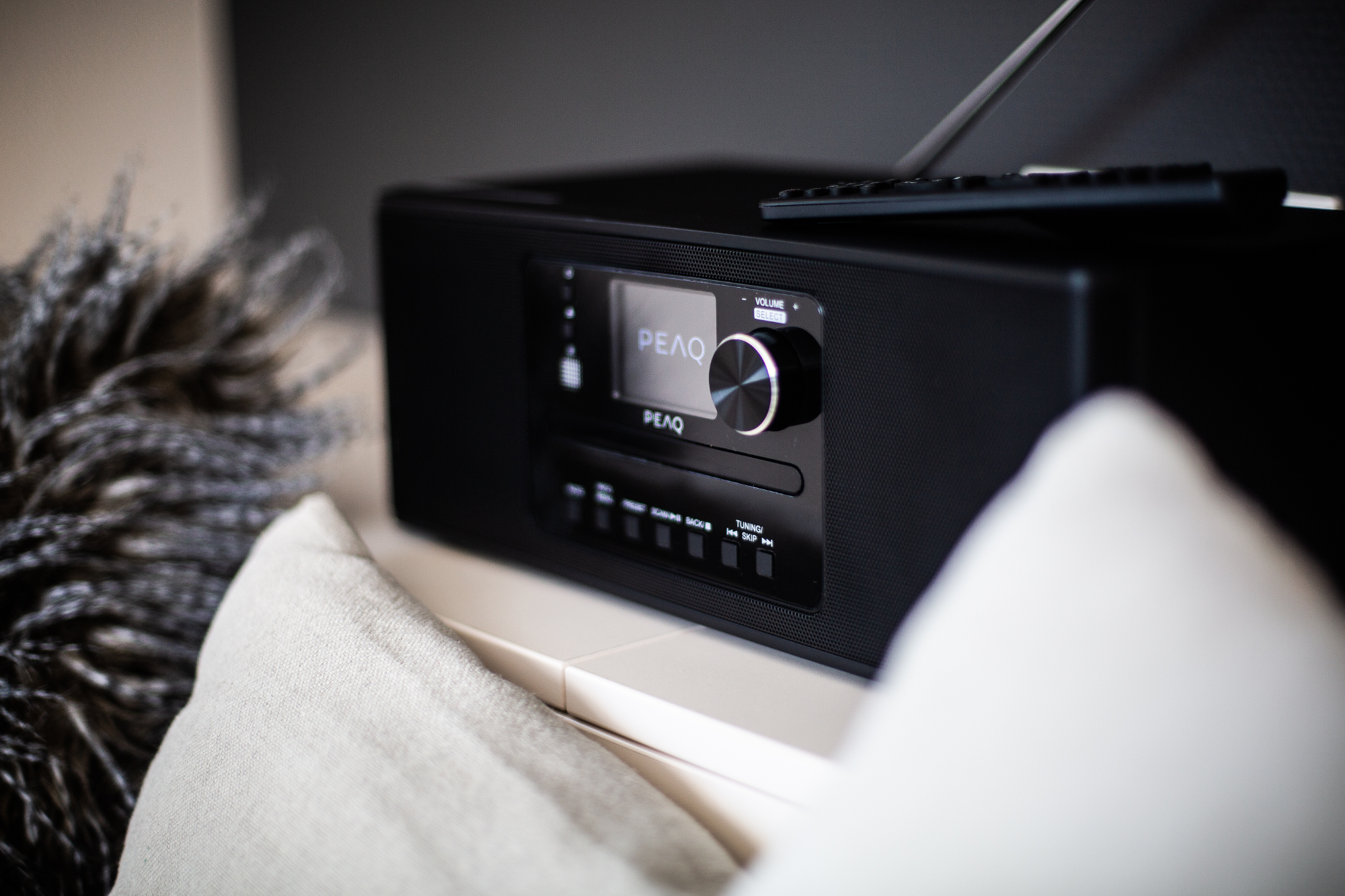 Une radio PEAQ noire avec télécommande sur une étagère, gros plan.