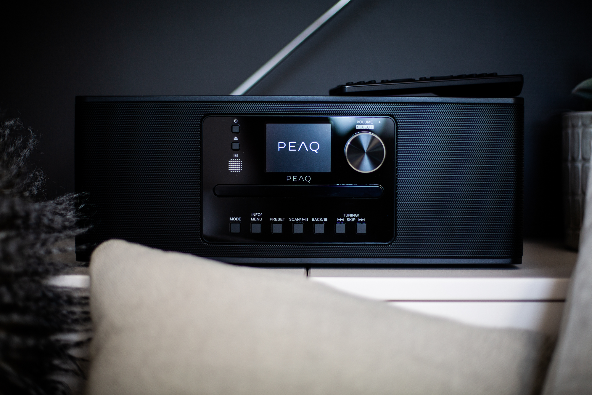 Radio PEAQ noire avec écran, bouton de volume et boutons.