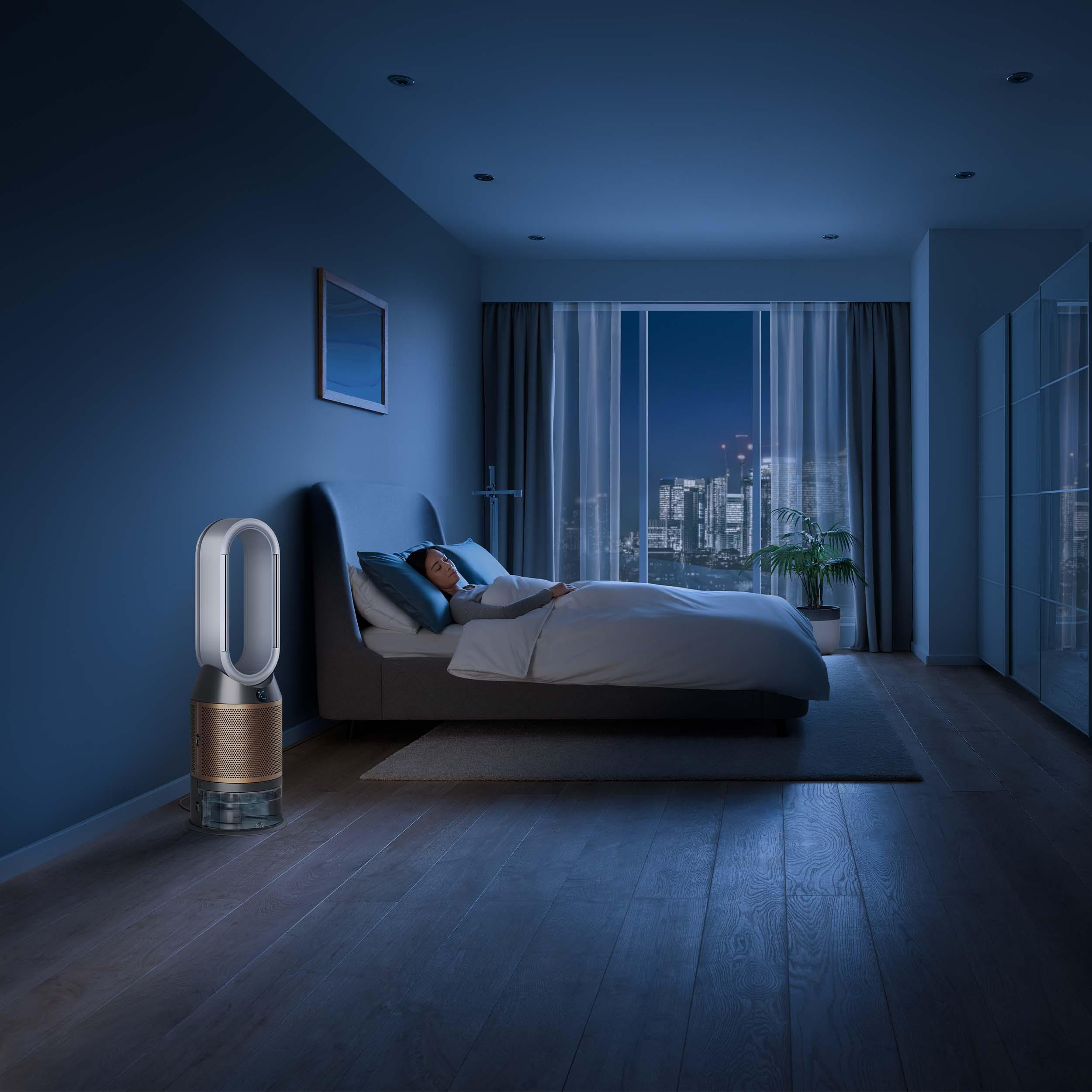 Schlafzimmer bei Nacht. Eine Person schläft im Bett. Ein Luftreiniger steht neben dem Bett.