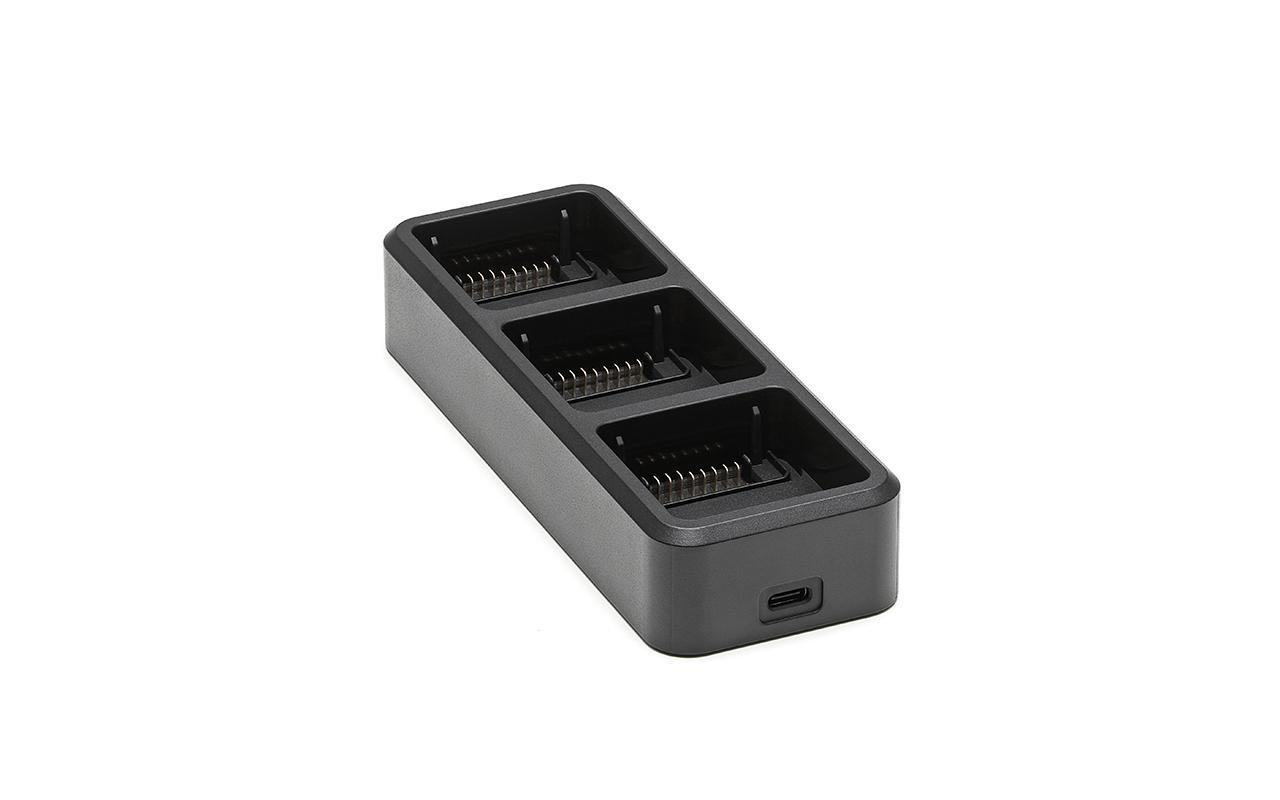 Eine schwarze Ladestation mit drei Steckplätzen für Batterien, auf weißem Hintergrund.