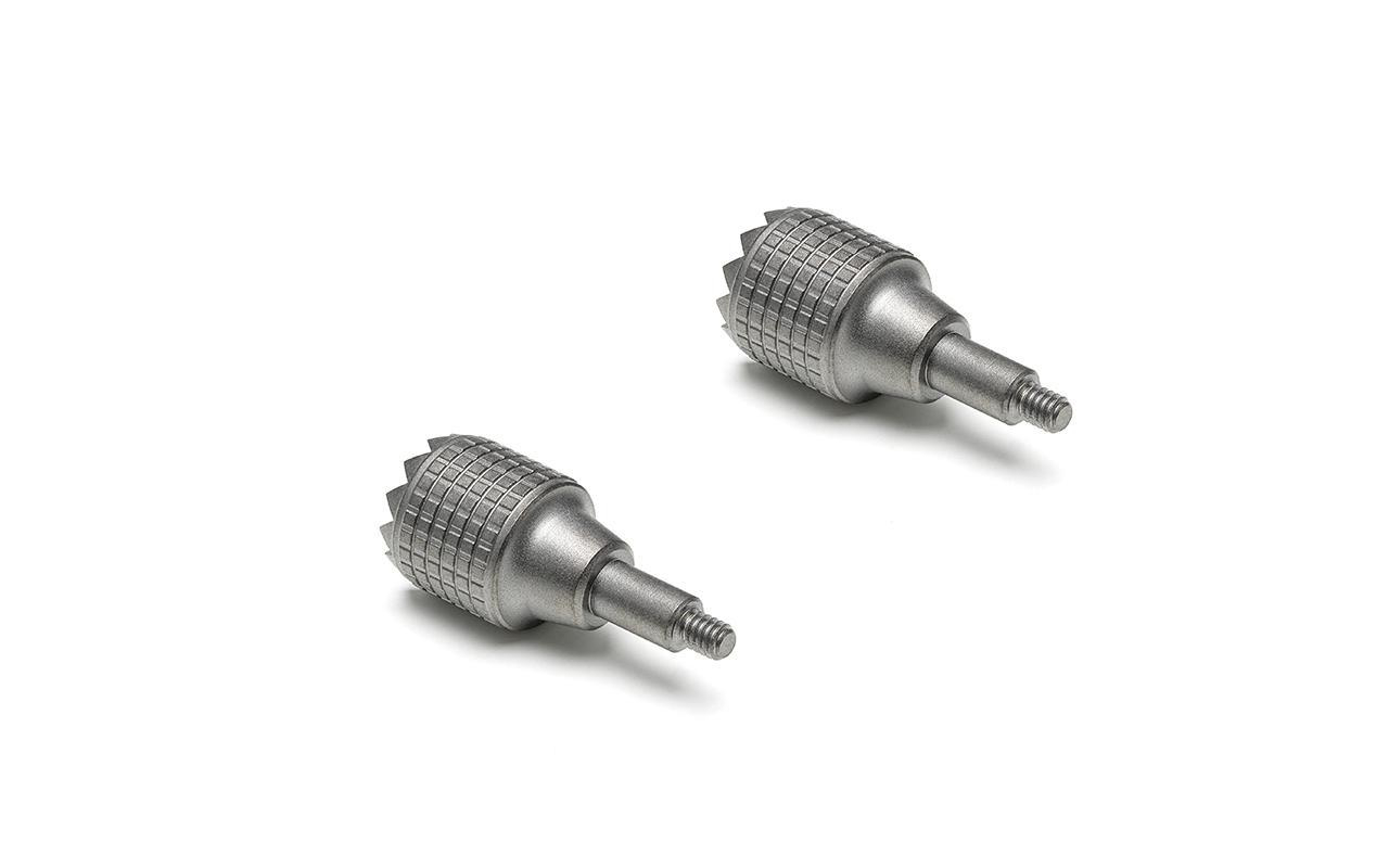 Zwei Metallschrauben mit strukturierten Köpfen, die auf weißem Hintergrund liegen. Sie sind glänzend.