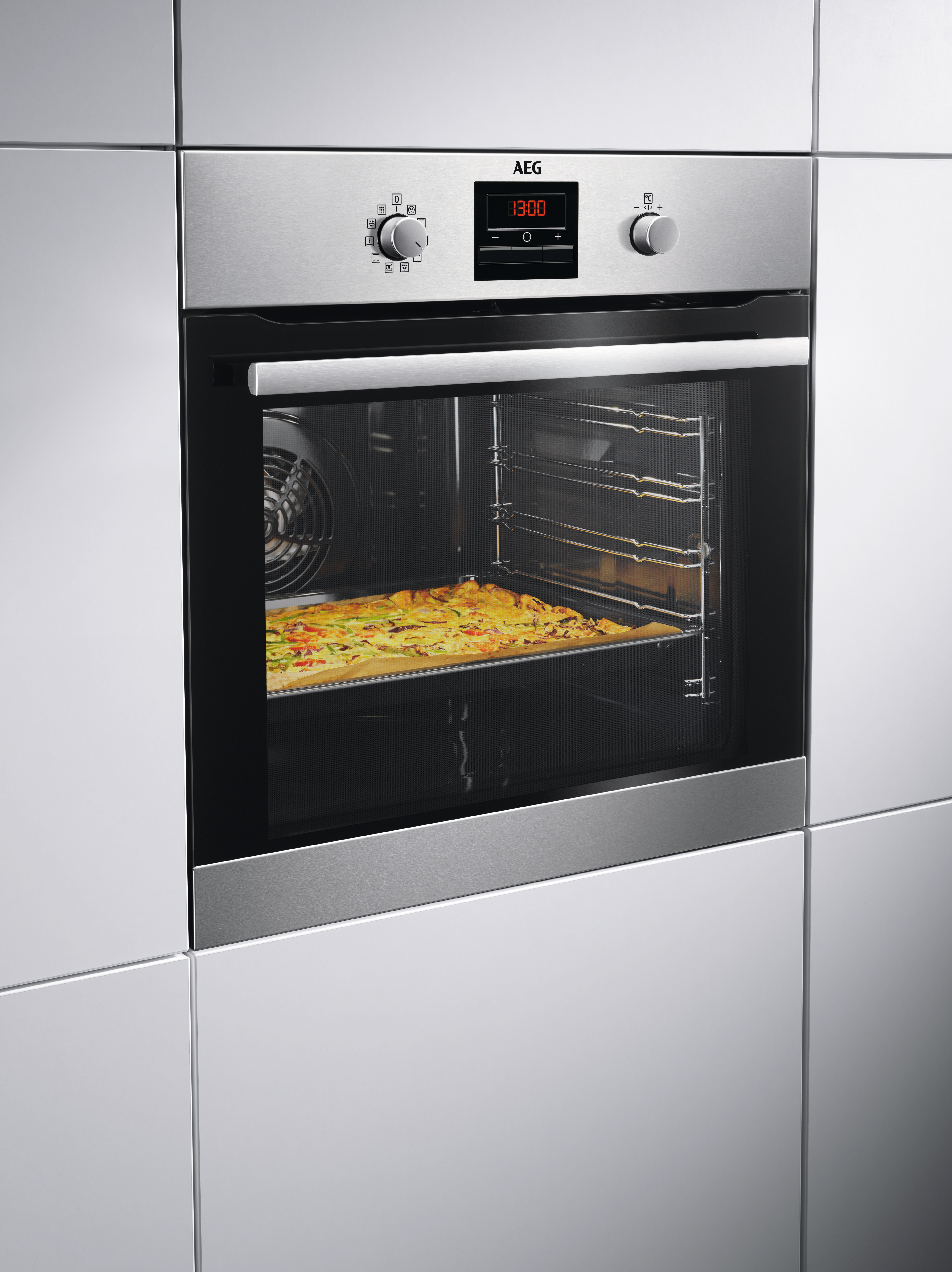 Edelstahl-AEG-Ofen mit Pizza im Inneren. Ofenbedienelemente sind sichtbar. Weißer Hintergrund.