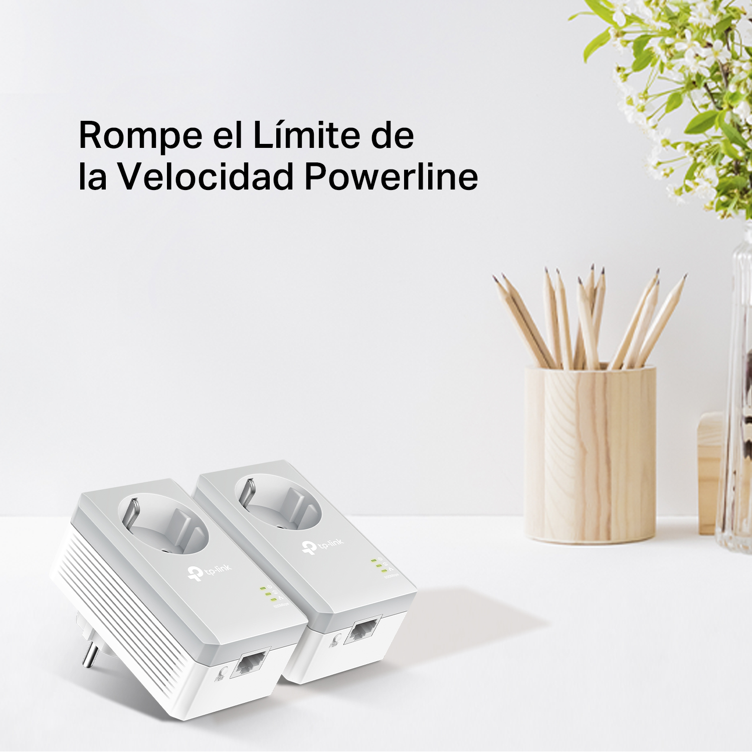 Dos adaptadores de línea eléctrica TP-Link en una mesa blanca. Un jarrón con lápices y flores al fondo.