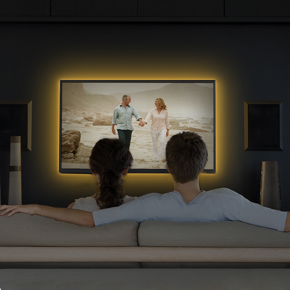 Pár tévét néz. A tévén egy tengerparti jelenet látható. Sárga fény világít a tévé és a hangszóró körül.