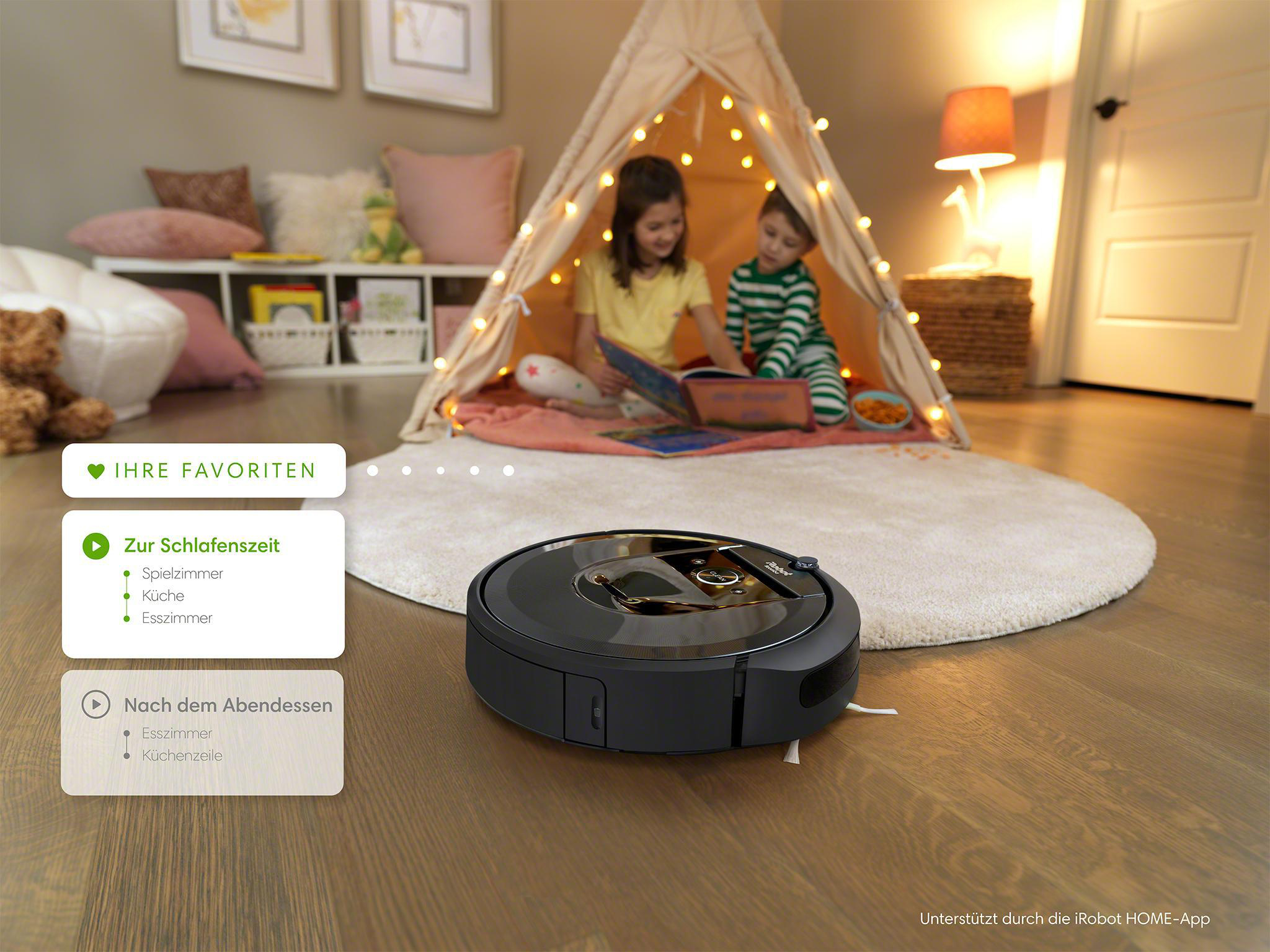Ein Roboter-Staubsauger auf einem Hartholzboden in der Nähe von Kindern in einem Spielzelt.