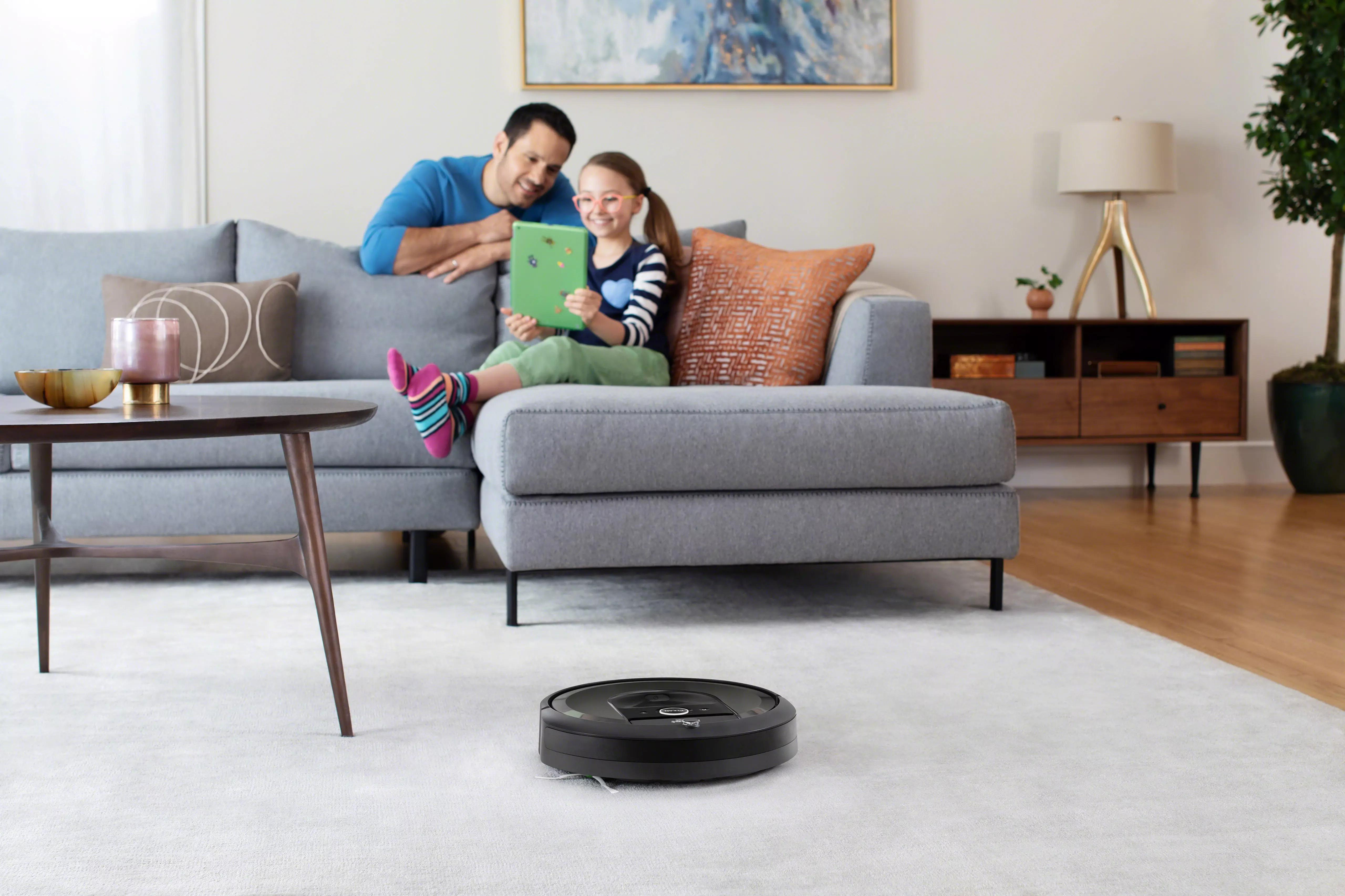 Familie im Wohnzimmer, Roboterstaubsauger reinigt Teppich, mit Couch und Couchtisch.