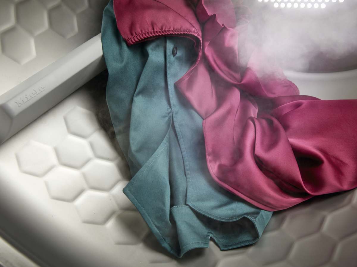 Kleidung, die in einer Waschmaschine dampft, mit einem Miele-Logo an der Seite.
