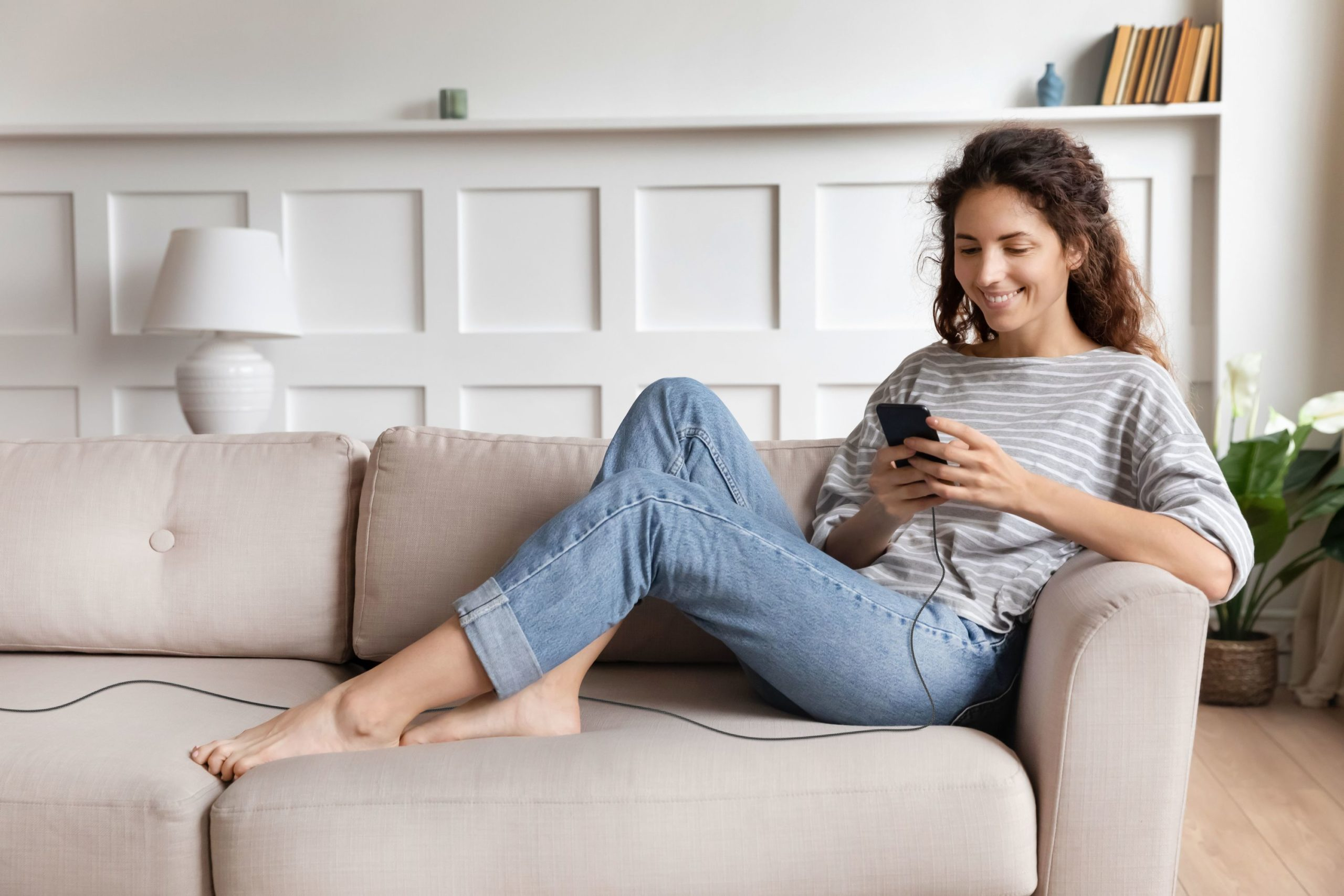 Eine Frau sitzt auf einem Sofa und benutzt ein Telefon, mit einem angeschlossenen Kabel.