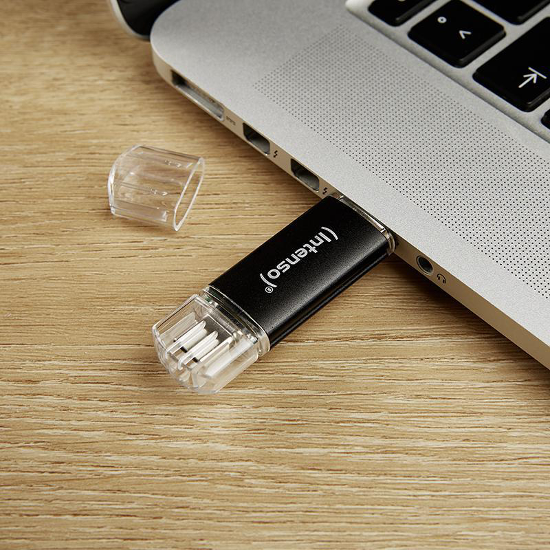 Ein schwarzer und klarer USB-Stick, der in den USB-Anschluss eines Laptops gesteckt ist.