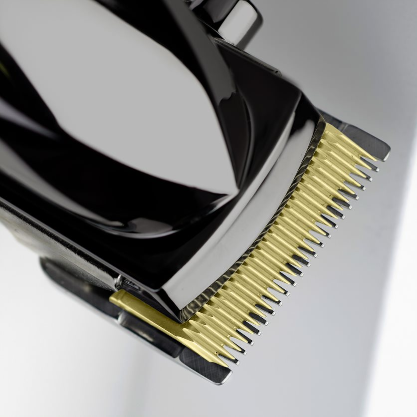 Close-up of a hair clipper with golden blades against a white background.