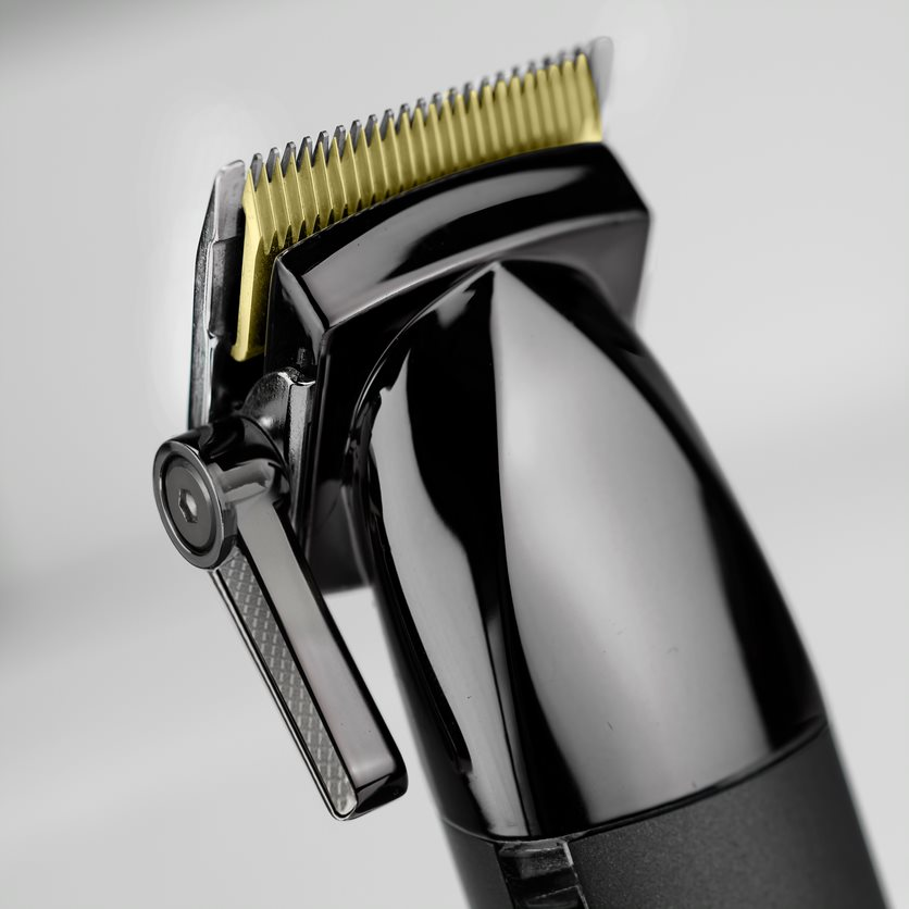 A black and gold hair clipper with a silver lever and a white background.