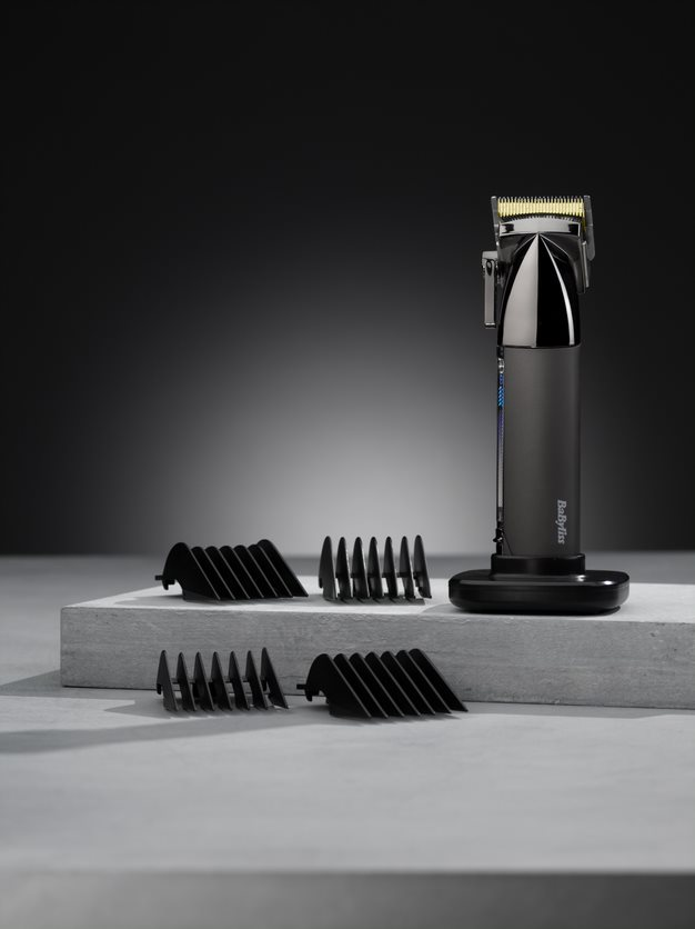 A black Babyliss hair clipper with black guide combs on a light surface.