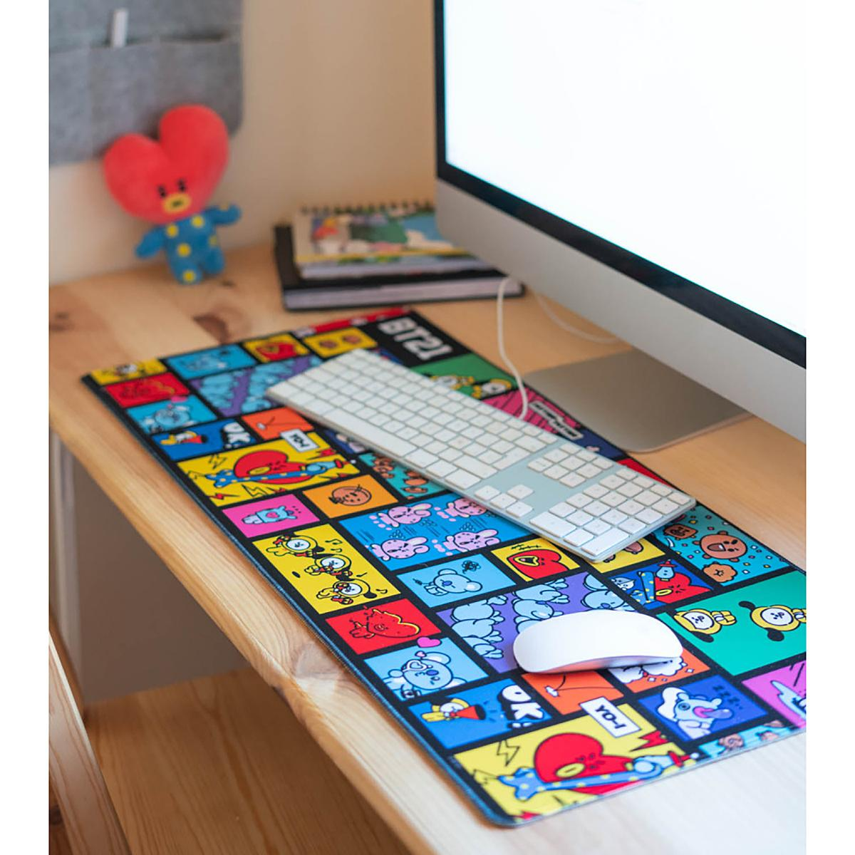 Ein Schreibtisch-Setup mit Tastatur, Maus und einer bunten Mousepad mit Cartoon-Bildern.