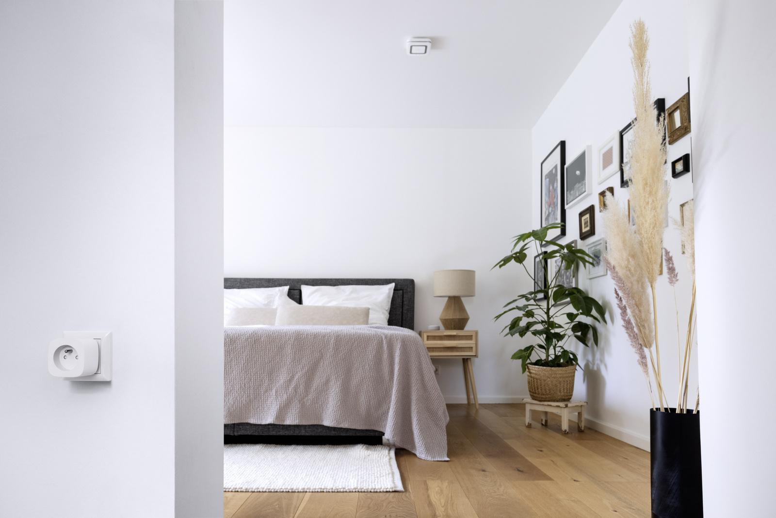 Ein gut beleuchtetes, modernes Schlafzimmer mit Bett, Nachttisch und Dekorationselementen.