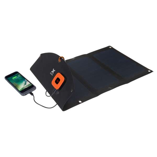 Ein schwarzes Solarpanel lädt ein Telefon auf. Es hat eine orangefarbene Powerbank und liegt auf schwarzem Untergrund.