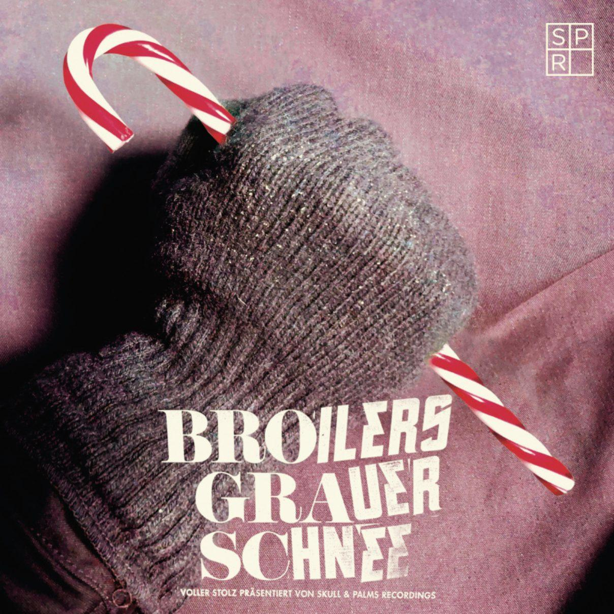 Behandschuhter Hand hält eine Zuckerstange. Albumcover für Broilers Grauer Schnee.