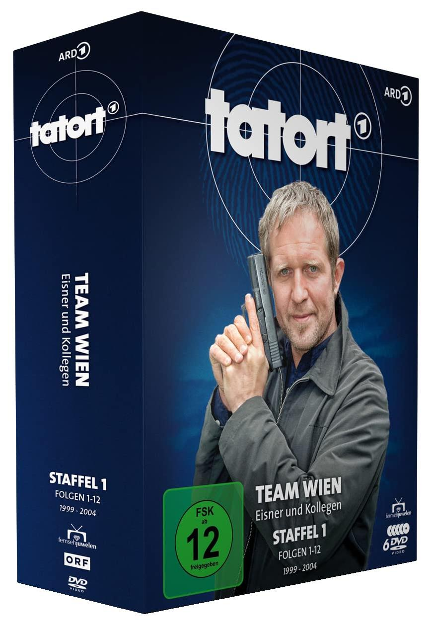 Ein Home-Security-Setup mit einer Kamera, einer Basisstation und einem Lautsprecher auf einem weißen Tisch.